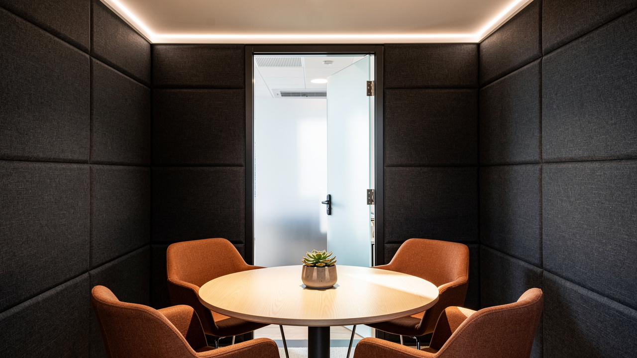 Calm and well-lit interior of an acoustic meeting pod with fabric panels